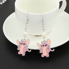 a pair of pink and white earrings on top of a plate next to a cup