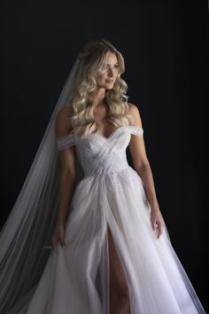 a woman in a white wedding dress posing for the camera with her veil over her head