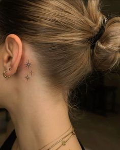 a woman with a star tattoo on her left side behind her ear, looking down at the ground