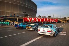 three cars are parked in front of a large sign that says next level on it