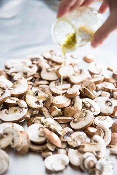 someone is pouring dressing onto mushrooms on a table