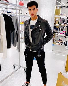 a young man standing in front of a rack of shirts and jackets at a clothing store