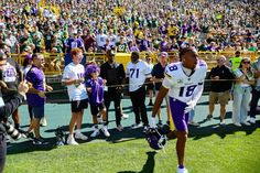 a football player is walking off the field with his helmet in hand and people behind him