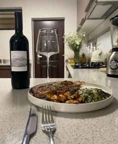 a white plate topped with food next to a bottle of wine