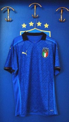 a soccer jersey hanging on a blue wall next to two hooks with gold stars and an italian flag