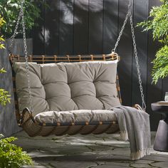 a swing chair hanging from the side of a wooden wall next to a potted plant