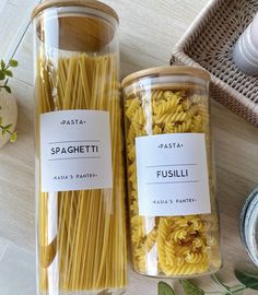 two jars filled with pasta sitting on top of a table