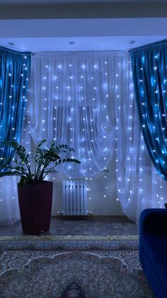 a living room with blue curtains and lights on the walls, plants in a pot