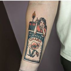 a person with a tattoo on their arm holding a lit candle in front of them