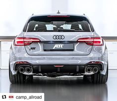 the rear end of an audi car in a garage with white walls and black flooring