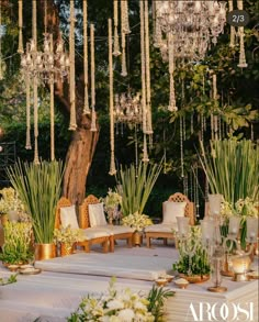 an outdoor wedding setup with chandeliers hanging from the ceiling and flowers in vases