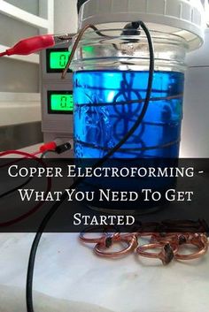 a blue container filled with liquid sitting on top of a table next to some copper rings