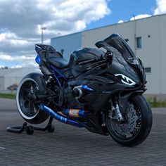 a black and blue motorcycle parked in front of a building with cloudy skies behind it