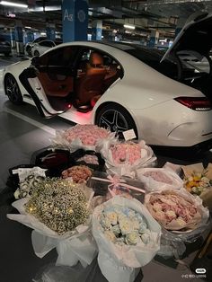 a bunch of flowers sitting on top of a table in front of a white car