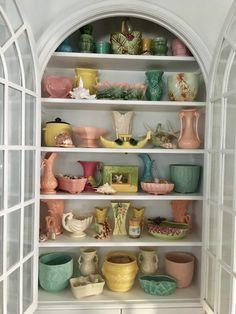 the shelves are filled with many different colored vases