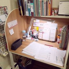 a wooden desk topped with lots of books and papers