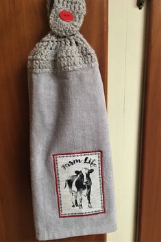 an oven mitt with a cow on it hanging from a door handle in front of a wooden door