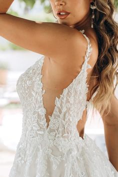 a woman in a wedding dress is holding her hair back and looking at the camera