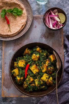 a pan filled with tofu and spinach next to a bowl of red onions