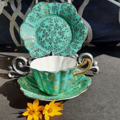 a tea cup and saucer sitting on top of a table next to yellow flowers