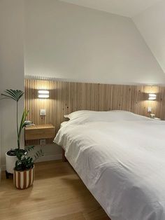 a white bed sitting in a bedroom next to a wooden headboard with two lamps on top of it