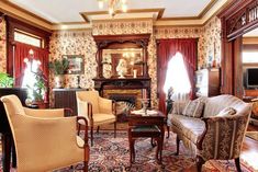 a living room filled with lots of furniture and walls covered in floral wall coverings