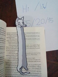 an open book with a drawing of a cat on top of it next to a piece of paper