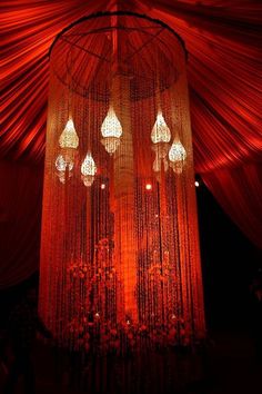 a chandelier hanging from the ceiling in a room with red curtains and lights