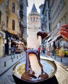 a person is spooning melted chocolate onto a plate in the middle of a street