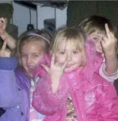 three children are posing for the camera with their hands up and fingers in the air