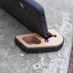 a cell phone with a wooden holder attached to it's back end on concrete