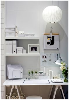 a white desk and chair in a room with shelves on the wall behind it,