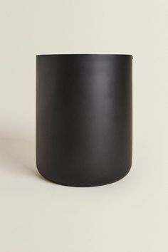 a black cup sitting on top of a white table