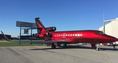 a red airplane sitting on top of an airport tarmac