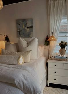 a white bed sitting in a bedroom next to two lamps on either side of the bed