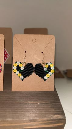 two pieces of beaded earrings on display in front of a card board with other items