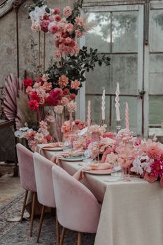 the table is set with pink flowers and candles for an elegant dinner or bridal party