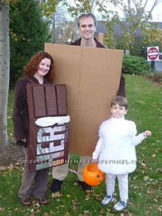 a man and woman in costumes standing next to a young boy holding a large cardboard box