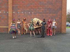 a group of women dressed in costumes standing next to each other near a brick wall