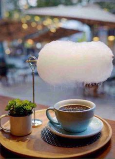 a cup of coffee sitting on top of a wooden table next to a white cloud