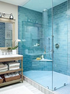 a blue tiled bathroom with a stand up shower