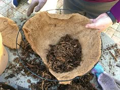 someone is holding a bowl full of composting material and some other things on the ground