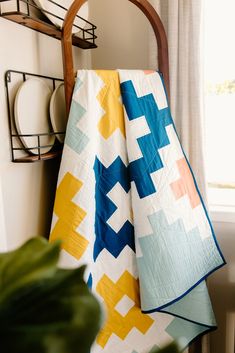 a blanket is hanging on the wall next to a potted plant and some plates