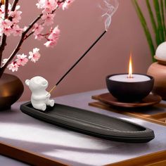 a white bear incense burner sitting on top of a tray next to a candle