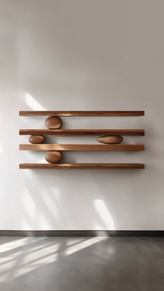 a wall mounted sculpture with wooden bowls on it's sides and three shelves in the middle