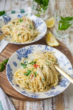 two plates filled with pasta and garnished with parsley on a wooden table