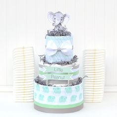 a three tiered baby shower cake with an elephant figurine sitting on top