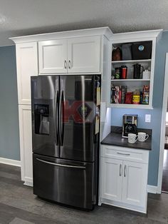 a black refrigerator freezer sitting inside of a kitchen next to white cabinets and drawers