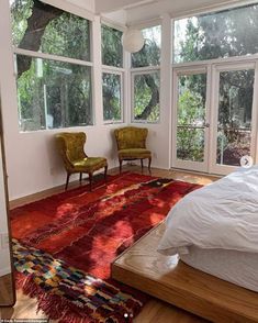 a bedroom with two chairs and a rug on the floor in front of large windows