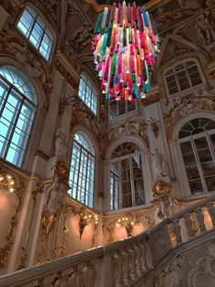 a chandelier hanging from the ceiling in a large room with windows and ornate decor